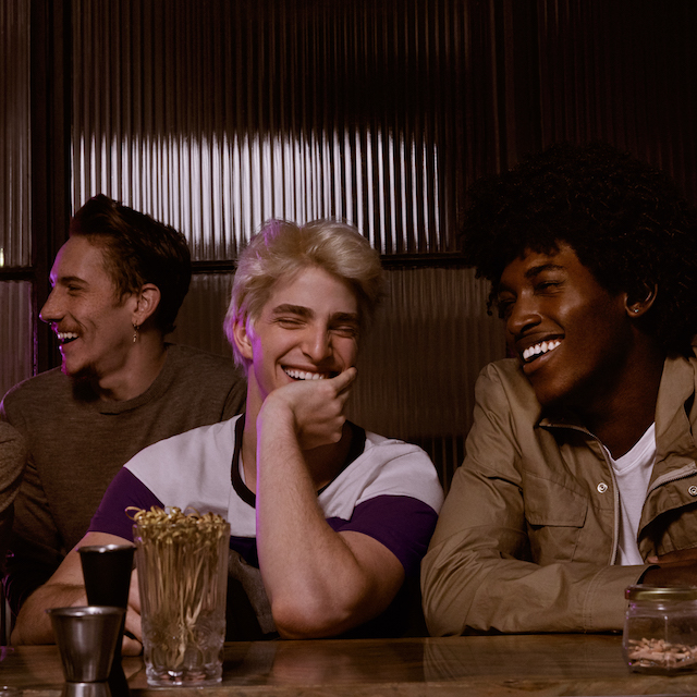 Atendimento ao cliente Nubank: foto de quatro pessoas sentadas num balcão. Elas estão sorrindo e brincando.