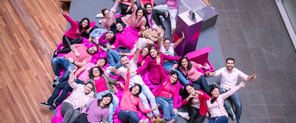 Foto aérea de grupo de pessoas vestindo rosa, sentados em uma arquibancada roxa