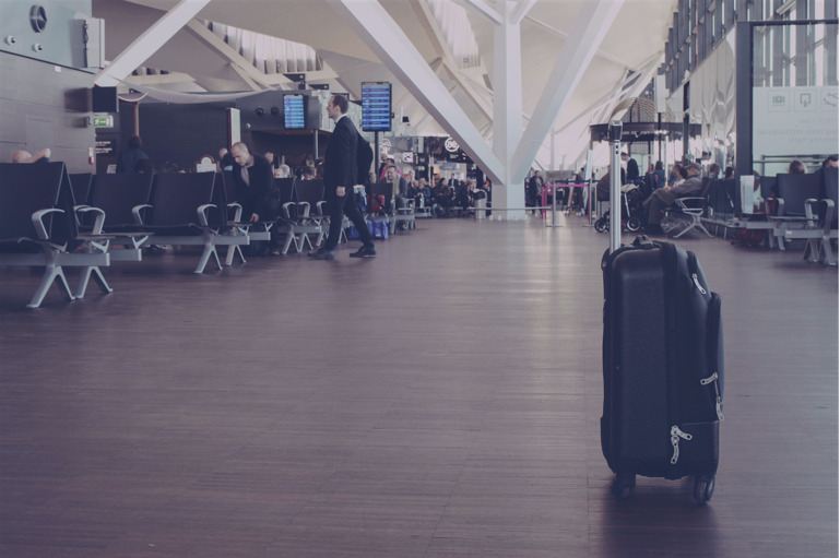 Imagem mostra o saguão de um aeroporto quase vazio e uma mala, sozinha, em primeiro plano