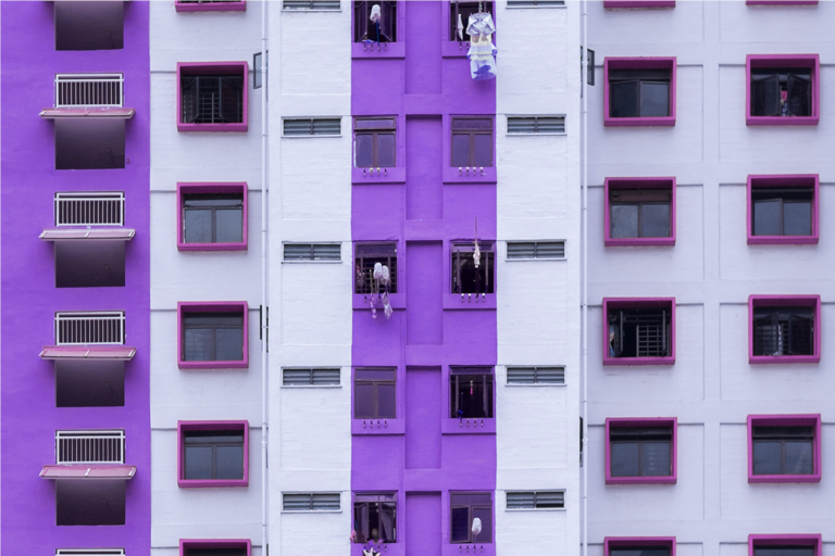 declarar Imposto de Renda pela primeira vez - Imagem mostra a fachada de um prédio com muitas janelas. A faixa central do prédio e as laterais são roxas. Os beirais das demais janelas são rosa escuro