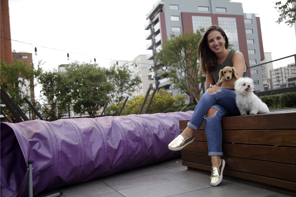 Jovem sentada em um terraço com dois cachorros ao seu lado