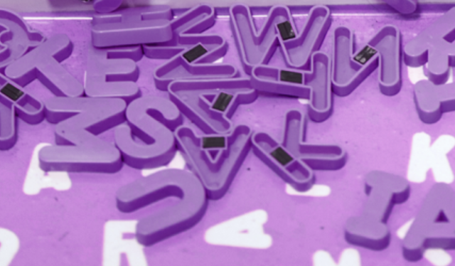 Várias letras magnéticas roxas caindo sobre um piso roxo com letras brancas