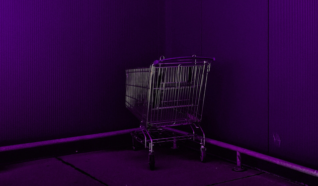 Desafio 52 semanas: um carrinho de supermercado roxo posicionado em um canto formado por duas paredes, ambas roxas.
