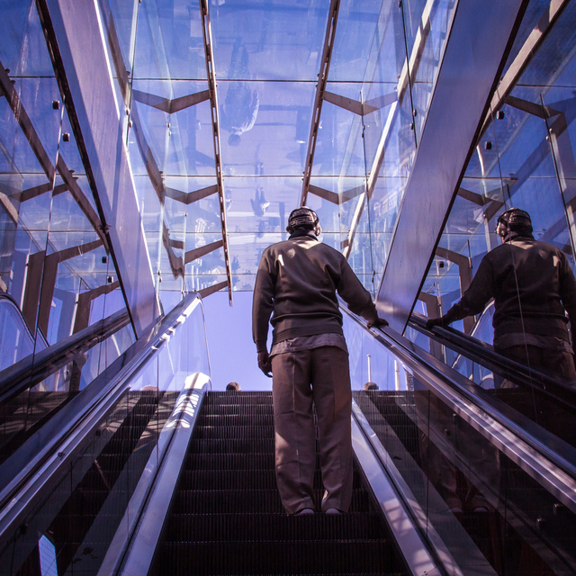 Desafio 50-15-35: Um homem sobe uma escada rolante coberta por um teto de vidro