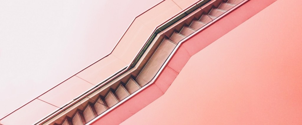 escada rolante na horizontal em frente a um fundo rosa claro