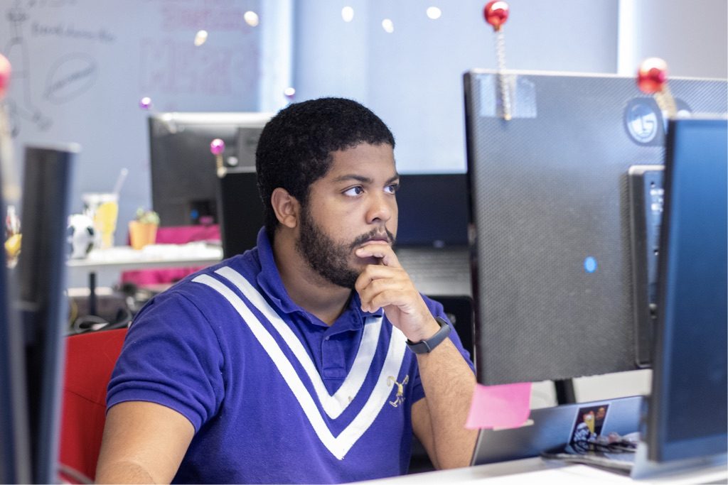 Vagas Nubank: jovem de camiseta azul sentado em frente ao computador