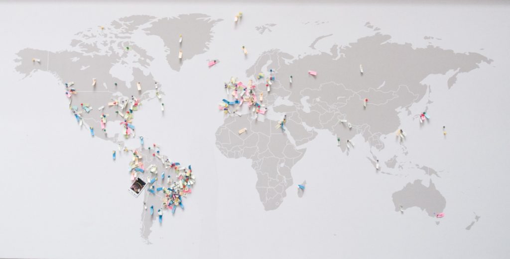 Mapa Mundi cinza com pins em diversos países e cidades.