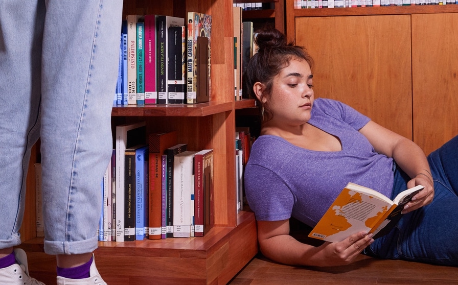 Como economizar dinheiro: jovem deitada no chão lendo um livro