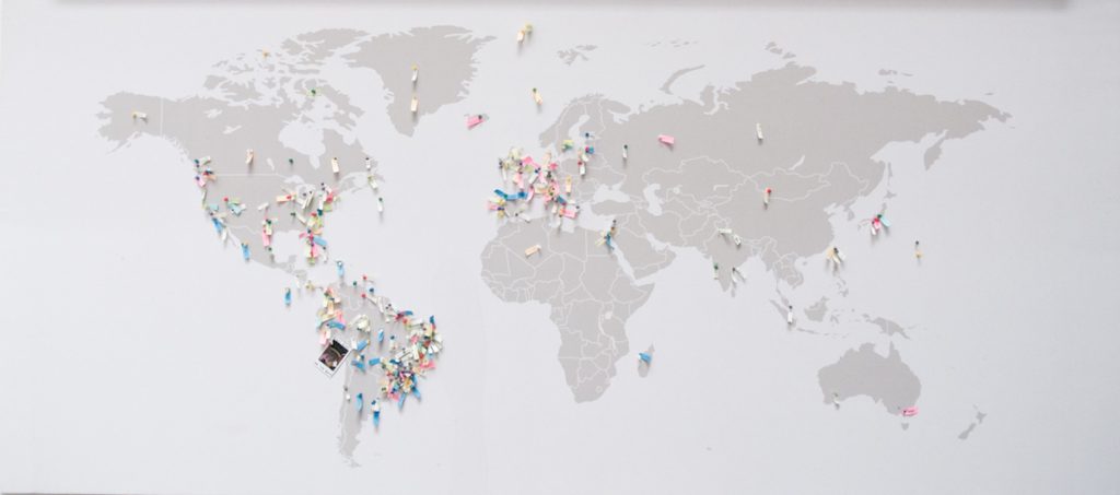 Mapa mundi com diversos alfinetes espalhados indicando lugares do mundo