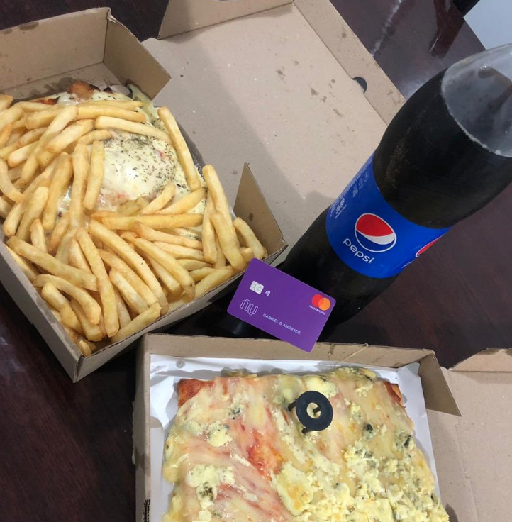 Duas pizzas e batatas fritas, ao lado de um refrigerante.