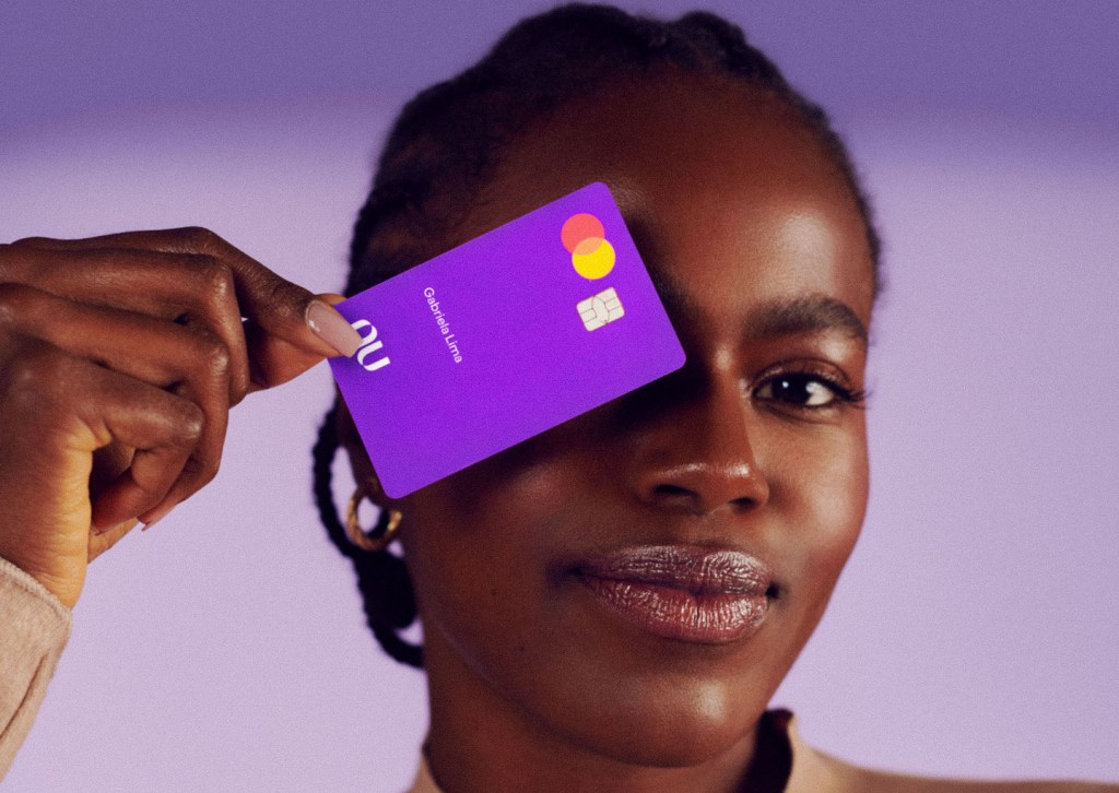 uma mulher segurando o cartão nubank perto do rosto