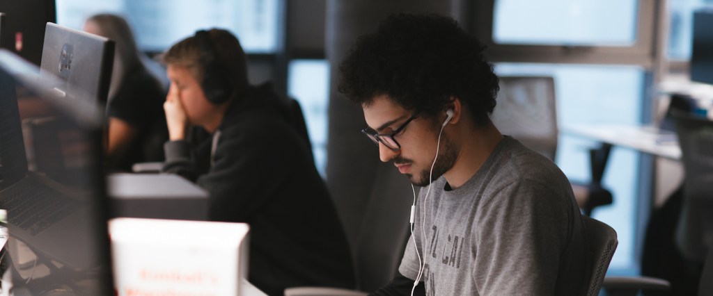 Data Science Nubank: foto de um Nubanker trabalhando em seu computador com fones de ouvido na orelha.