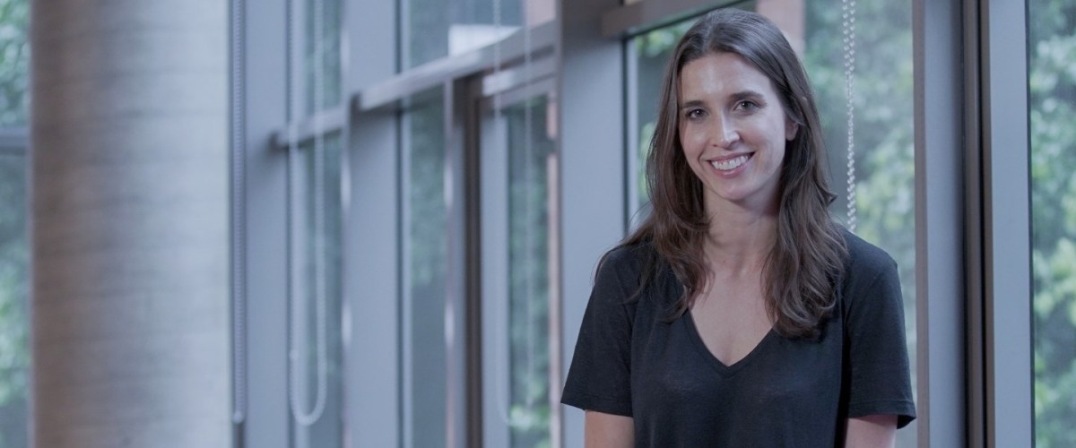 Product Manager: Foto de Aly sentada sorrindo, usando uma camiseta preta