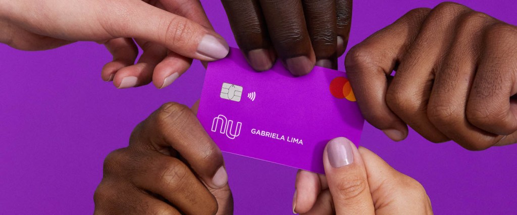 Nubank 30 mil clientes 60 anos : no fundo roxo, cinco mãos seguram o cartão Nubank