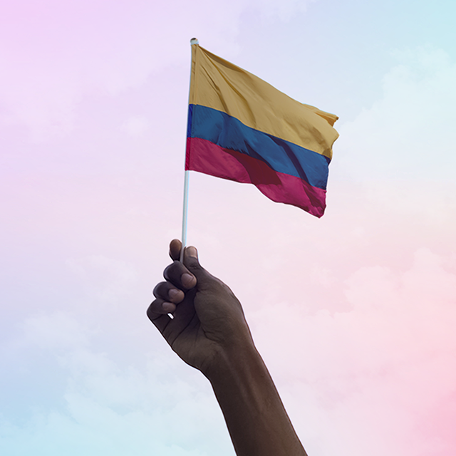 Mão segurando uma bandeira colombiana