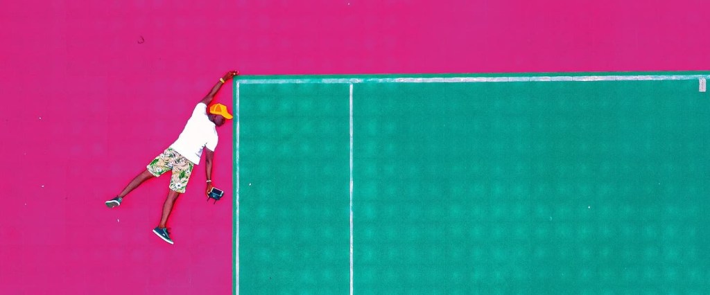 Aprender finanças com jogos: no fundo rosa, ilustração de um homem se segurando na ponta de uma quadra de tênis