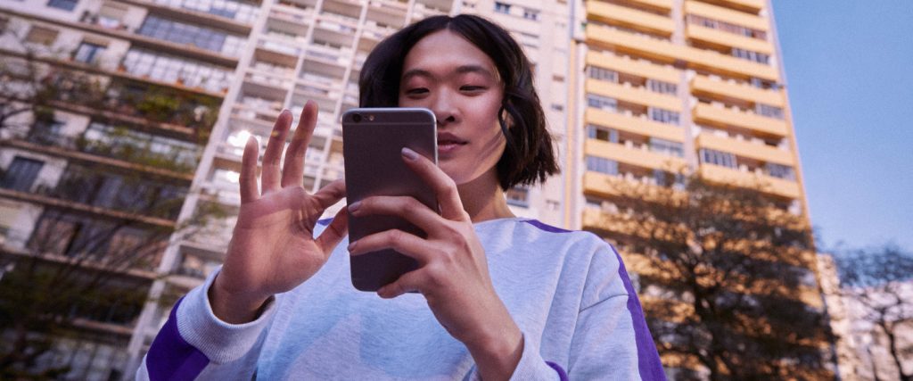 Chaves Pix no Nubank: mulher asiática segurando um celular em frente a um prédio