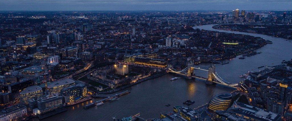 Foto aérea de Londres, com o io e os prédios iluminados ao redor