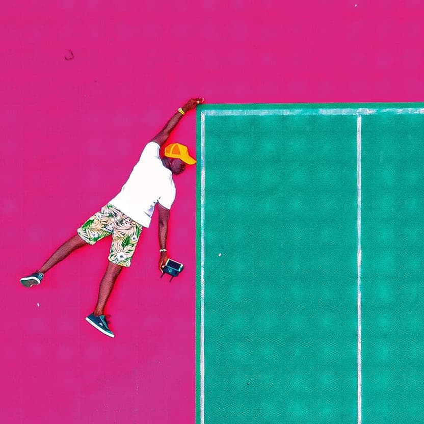 no fundo rosa, imagem aérea de um homem se segurando na ponta de uma quadra de tênis enquanto segura um drone