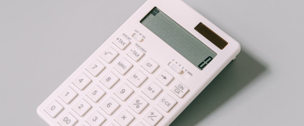 Custo fixo: fotografia de uma calculadora branca com o número zero na tela sobre uma superfície cinza clara
