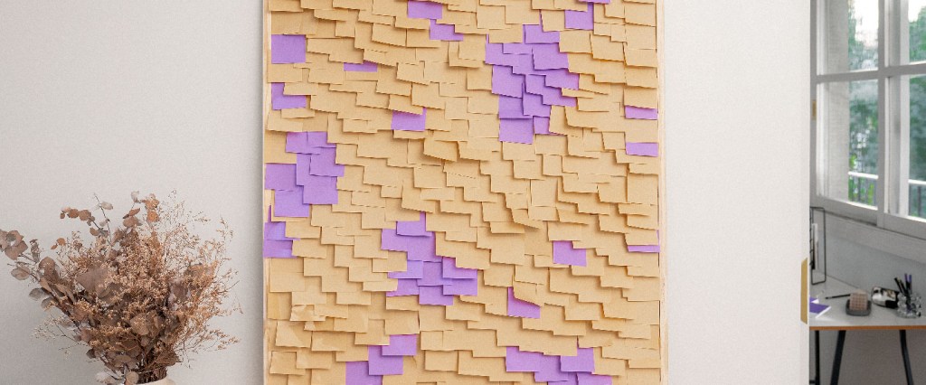 Imagem de uma sala, com um painel recheado com post-its amarelos e roxo. Ele está posicionado sobre uma mesa e, ao lado dele, há um vaso decorativo com folhas secas. Ao fundo, há também uma janela aberta e uma mesa de escritório.