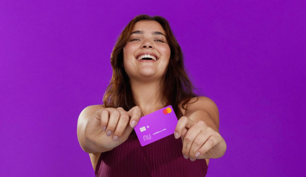 foto de uma mulher segurando o cartão Nubank enquanto sorri