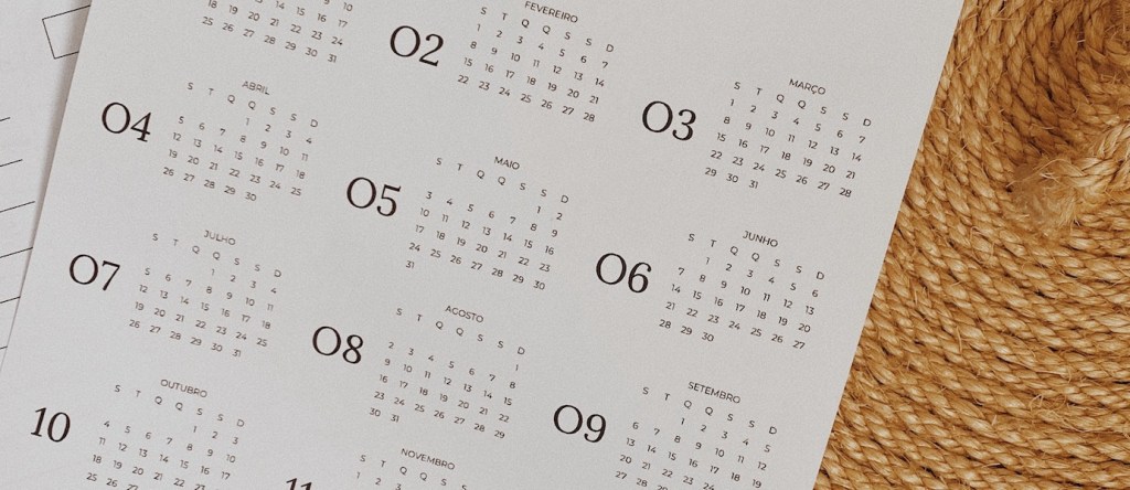 Calendário Saque FGTS 2021: fotografia de um calendário sobre uma mesa branca ao lado de um chapéu de sisal e uma caneta (Crédito: Olive Tatiane)