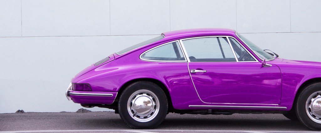 golpe venda de carro barato: um veículo roxo estacionado em frente de uma parede cinza