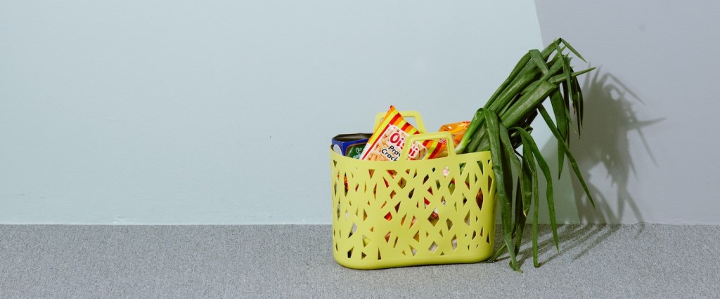Uma cesta de compras amarela com produtos dentro. Foto de yi_sk via Unsplash