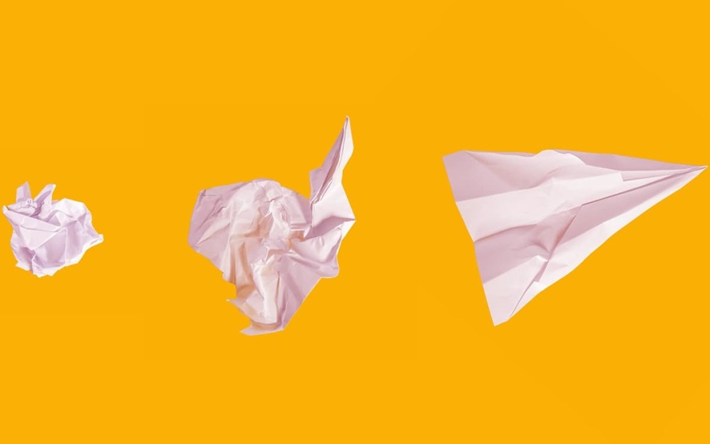 5 erros entrevista emprego: foto de papeis brancos amassados e formando um avião de papel progressivamente com fundo amarelo. @mattwridley/Unsplash