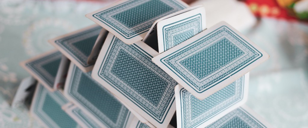 Grupo de Pix de 1 real: fotografia de um castelo de cartas de baralho com fundo azul e branco