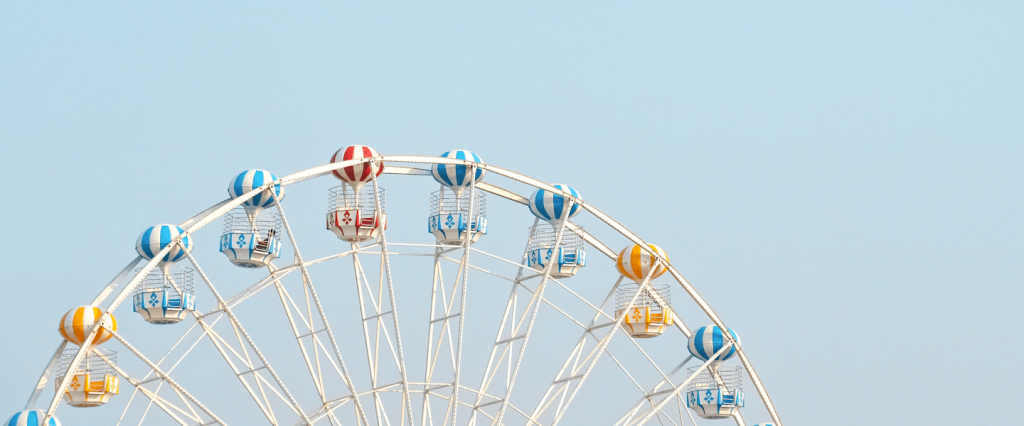 10 palavras que você precisa saber para uma entrevista de emprego. Roda gigante branca com assentos coloridos em forma de balão, céu azul ao fundo. Créditos: Sunisa Misa - Unsplash