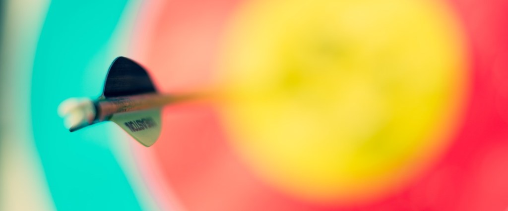 Como pagar com Pix: fotografia de um dardo enfincado em um alvo amarelo no centro, vermelho e azul. Créditos da imagem: Ricardo Arce