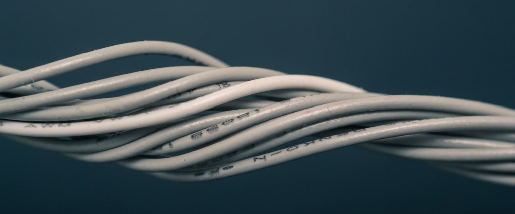 Pix offline: fotografia de fios brancos de plástico emaranhados e torcidos num fundo azul petróleo. Créditos da imagem: Steve Johnson