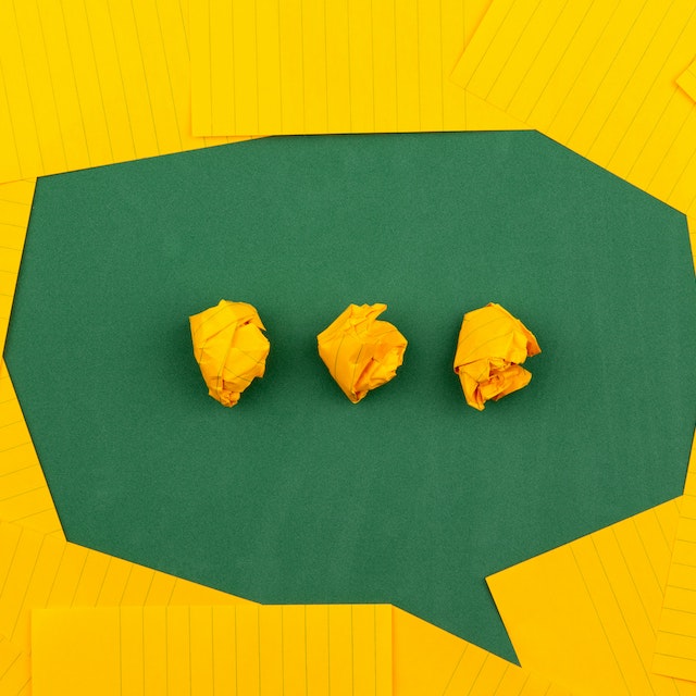 Pix poderá ser usada em aplicativos de mensagem: cartões amarelos dispostos formando um balãozinho de conversa verde no meio. Ao centro, três bolinhas amarelas de papel. Créditos da imagem: Volodymyr Hryshchenko