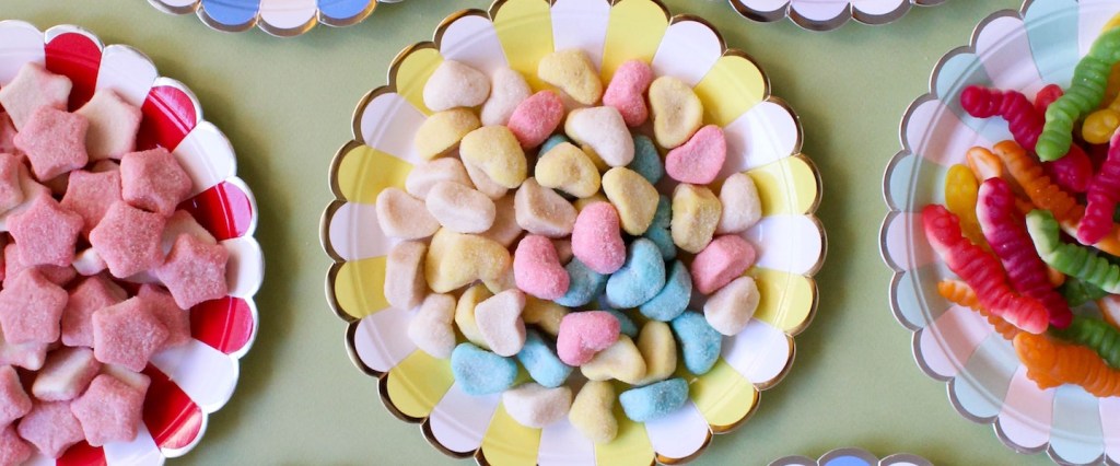 FoF: Vista de cima de uma mesa com vários pratinhos coloridos, cada um repleto de doces diferentes. Foto: Analia Baggiano.