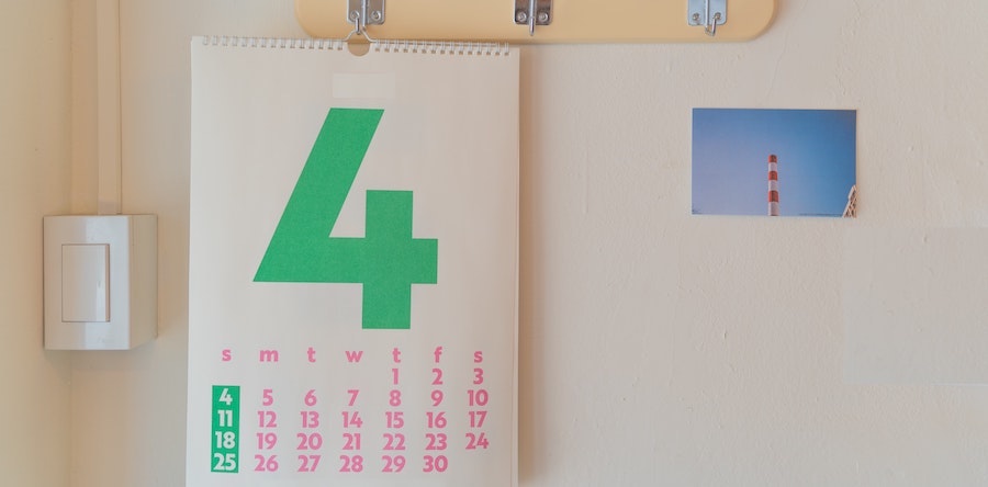 Imagem de um calendário de parede com papel branco, letras rosas e um número 4 verde bem grande, ocupando mais da metade do espaço. Foto via Unsplash.