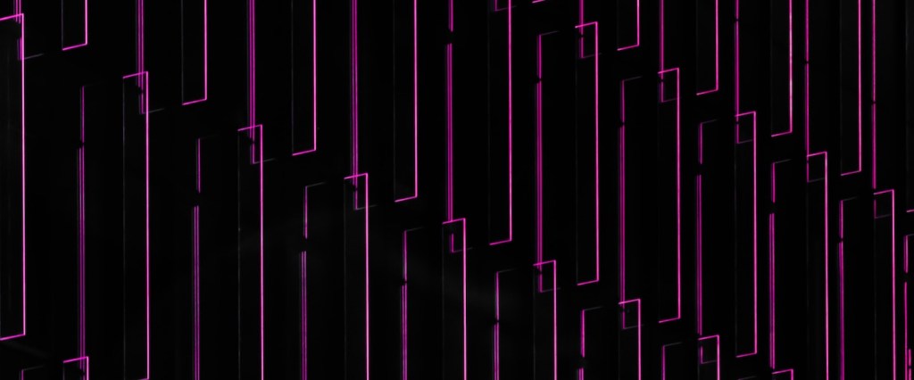 CBDC: fotografia de luzes retas roxas e rosa no fundo preto. Créditos da imagem: Pawel Czerwinsk