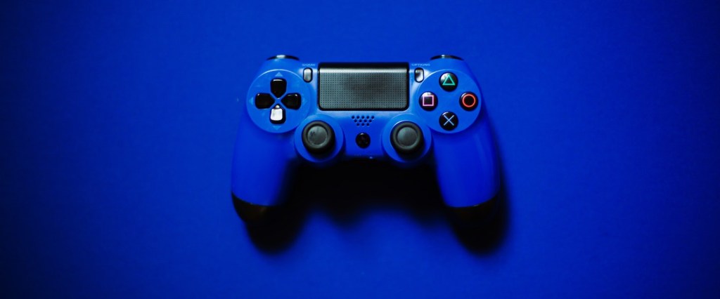 Como transformei minha paixão por games em carreira, com Henrytado: no fundo azul, fotografia de um controle de videogame azul. Créditos da imagem: Sean Ston