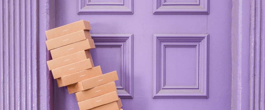 Pix bate recorde véspera Dia dos Pais: fotografia de caixas de papel pardo empilhadas em frente a uma porta lilás. Créditos da imagem: Curology