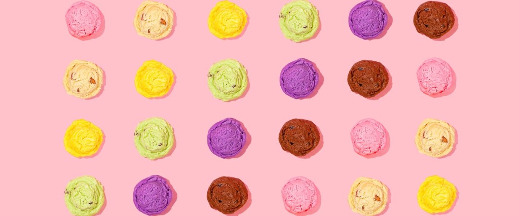 Clima e economia: fotografia de bolas de sorvete coloridas, dispostas simetricamente no formato de um quadrado, sobre um fundo rosa claro. Créditos da imagem: Amy Shamblen