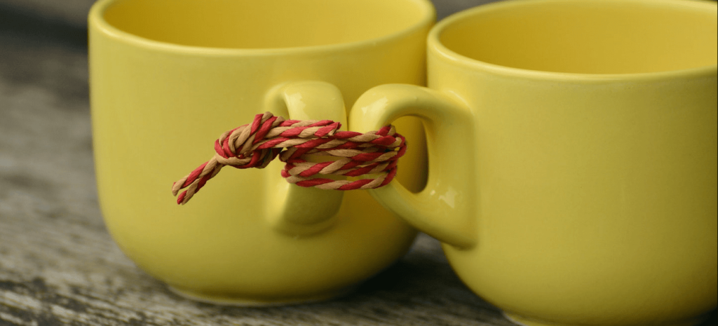 O que é cheque caução? Duas xícaras amarelas, amarradas pela asa com uma linha de cor vermelha e laranja. Créditos: Pixabay