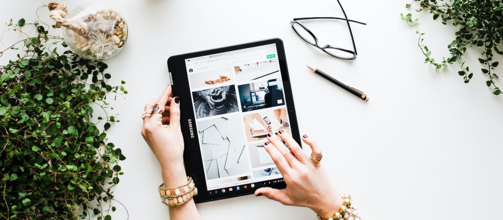 aplicativos de vendas: mulher usa um Ipad manuseando o que parece ser uma loja online ou fotos. Imagem: Brooke Lark/ Unsplash