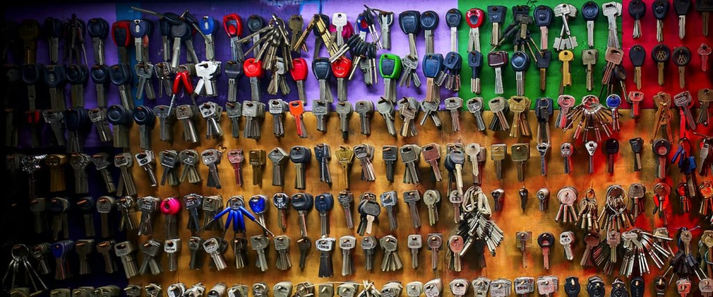 Vai compartilhar as suas chaves Pix? Cuidado. Diferentes tipos de chaves penduradas em uma parede colorida, lado a lado. Créditos: Chuncli, unsplash.