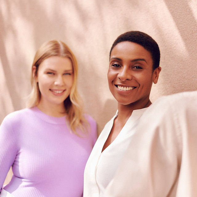 Nubank compra startup Olivia: Na imagem, três pessoas sorrindo. A primeira é uma mulher loira com uma blusa de manga comprida lilás, a segunda é uma mulher negra de cabelo curto e blusa branca, e a terceira pessoa é um homem negro, também de cabelo curto, vestindo uma camisa branca.