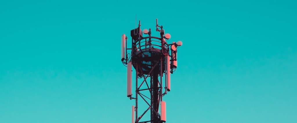 Leilão 5G: fotografia de uma torre com antenas no fundo azul. Créditos da imagem: Thomas Millot