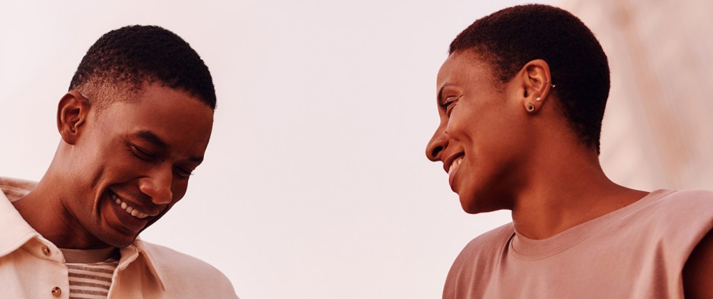 Imagem mostra um homem e uma mulher negros sorrindo.