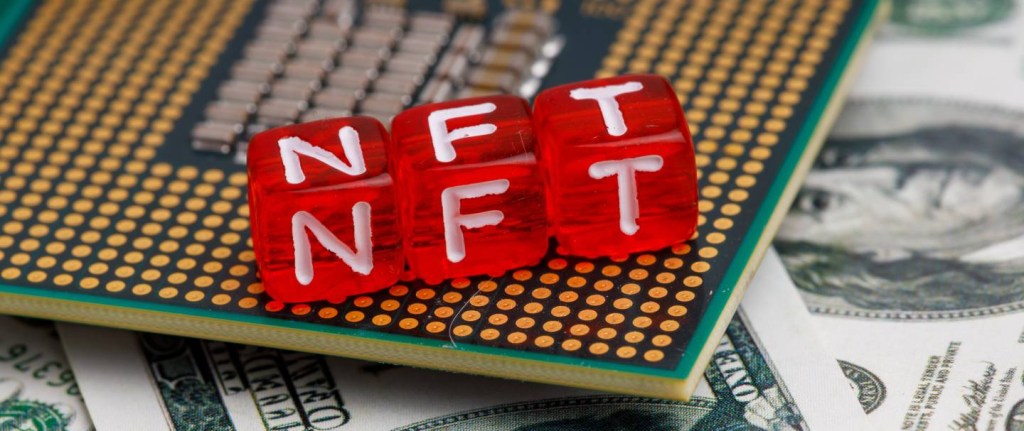 NFT criptomoeda - Imagem mostra três dados vermelhos com as letras N, F, T. Eles estão em cima de um chip de computador e de notas de dólar.