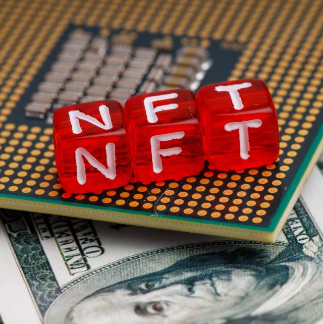 NFT criptomoeda - Imagem mostra três dados vermelhos com as letras N, F, T. Eles estão em cima de um chip de computador e de notas de dólar.