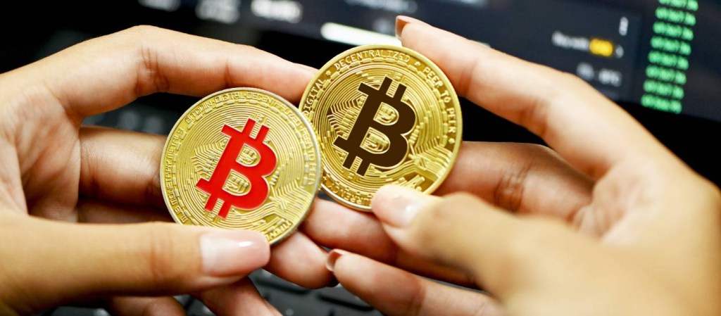O que eu posso fazer com criptomoedas - Imagem mostra duas mãos segurando duas moedas douradas e representam bitcoins.